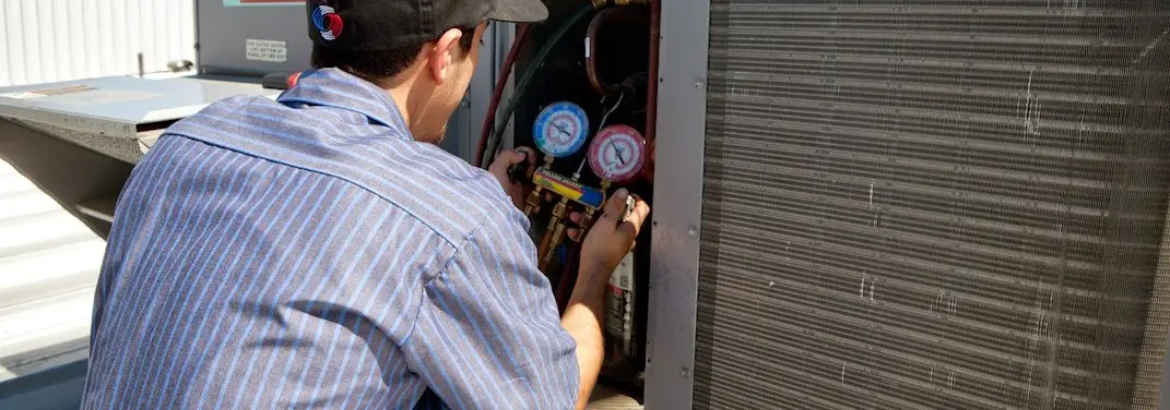 HVAC technician servicing a condenser unit in Presque Isle